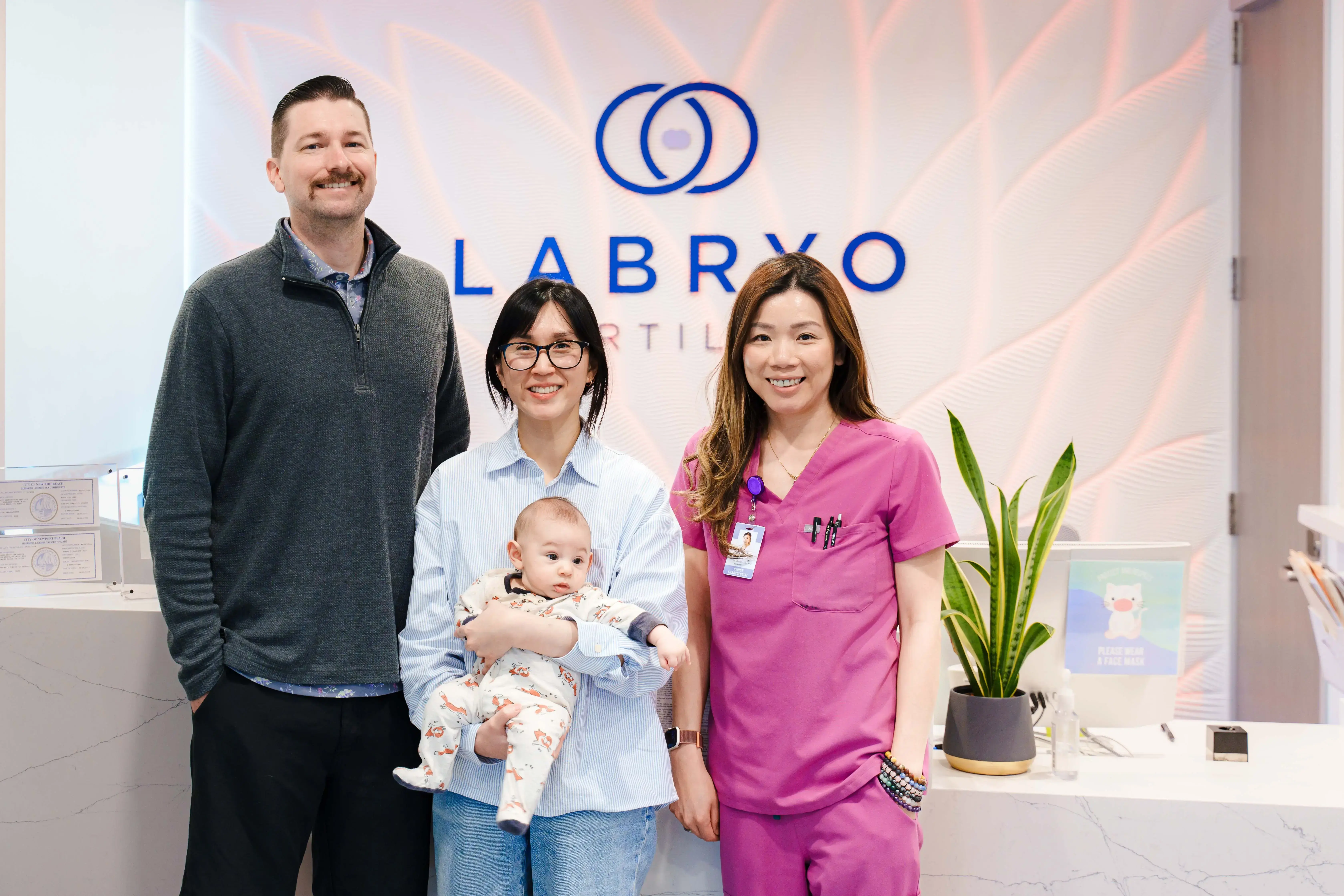 Happy couple with their baby with their embryologist, Molly